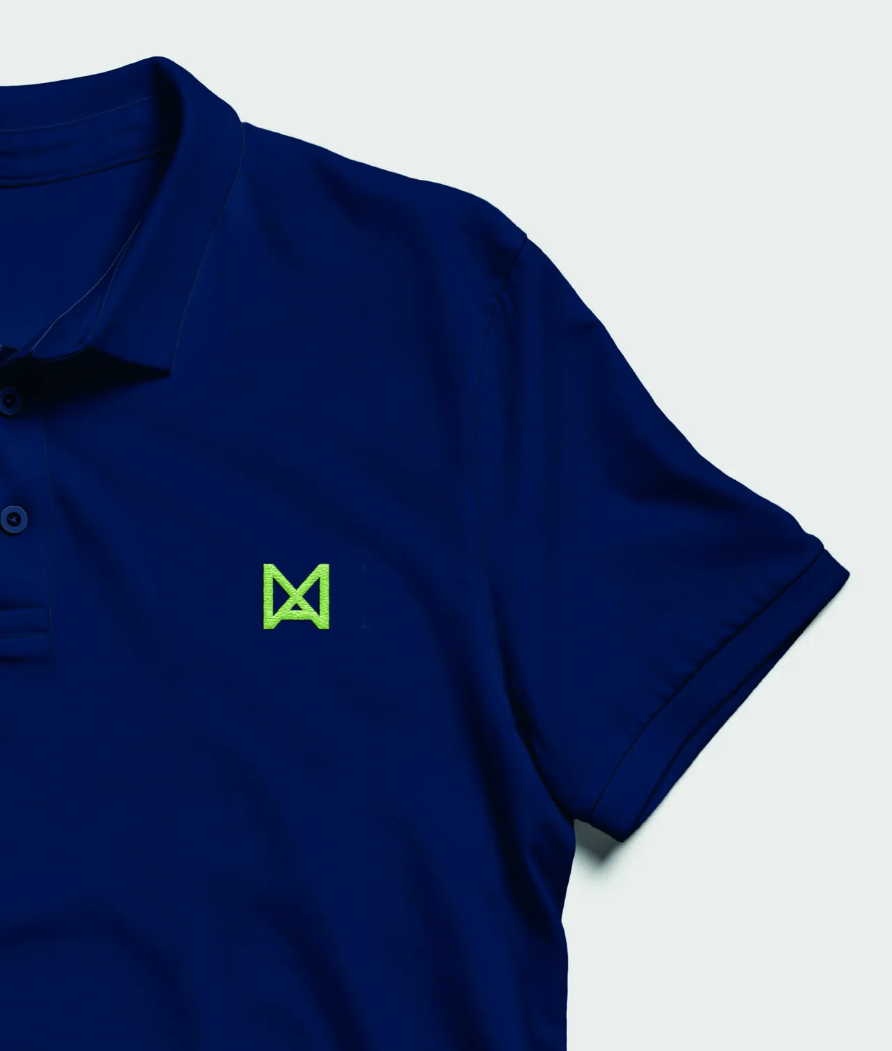 A navy polo shirt with the Navix logomark embroidered in Brand Green on the chest.