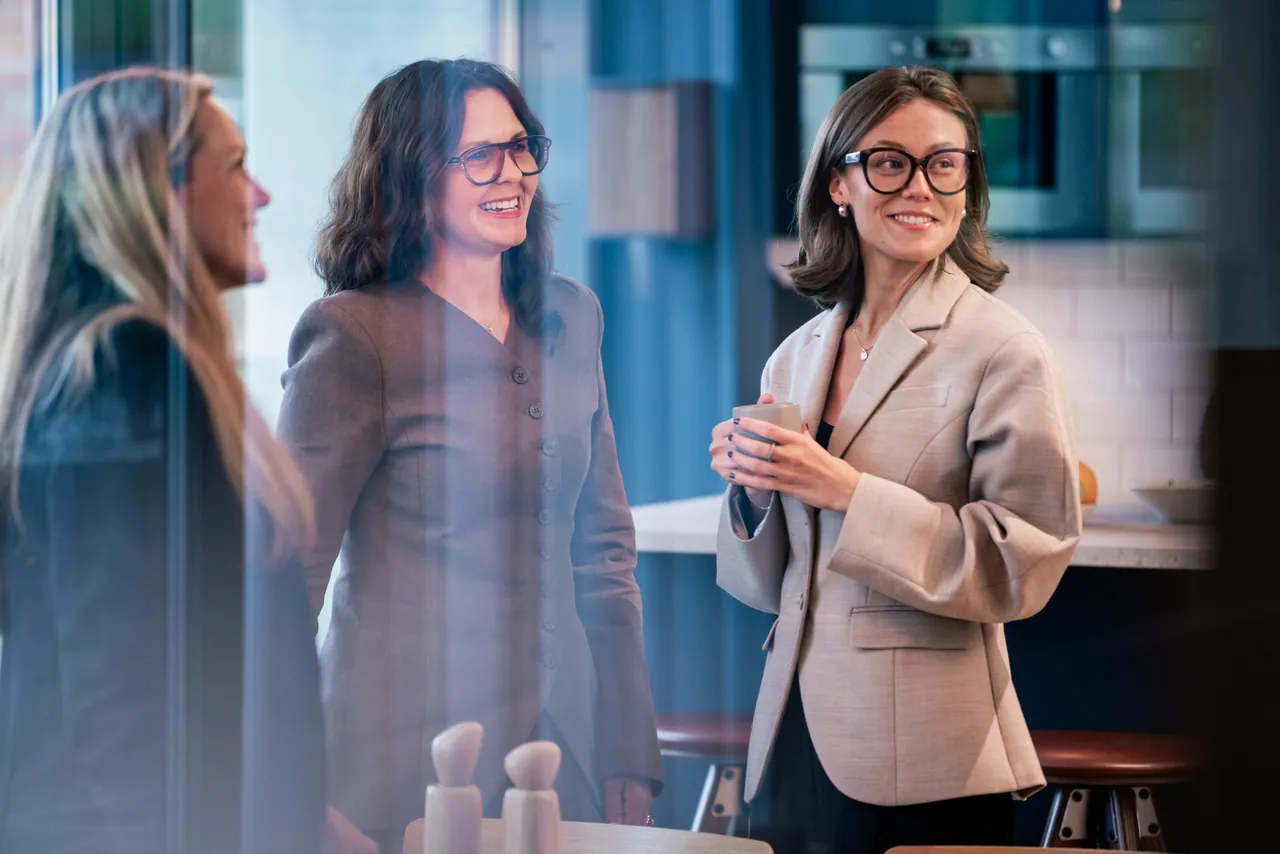 Three colleagues talking and smiling together in the office